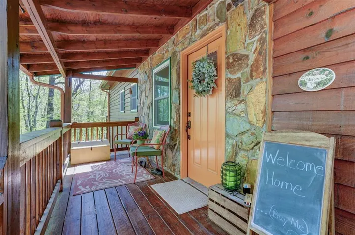 Covered wood-plank porch with wood railing, stone facade, and wood siding