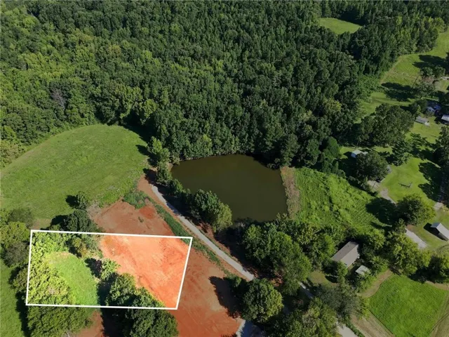 Rural land featuring a natural pond and surrounding wooded areas