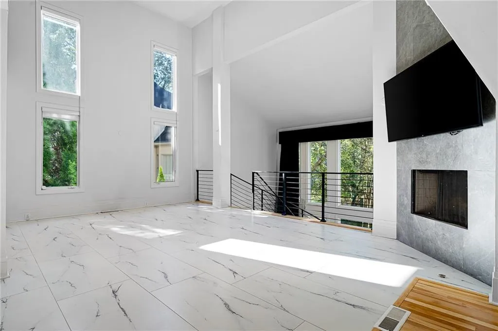 Unfurnished living room with a towering ceiling, marble look tiles, and a fireplace Unfurnished living room with a towering ceiling, marble look tiles, and a fireplace