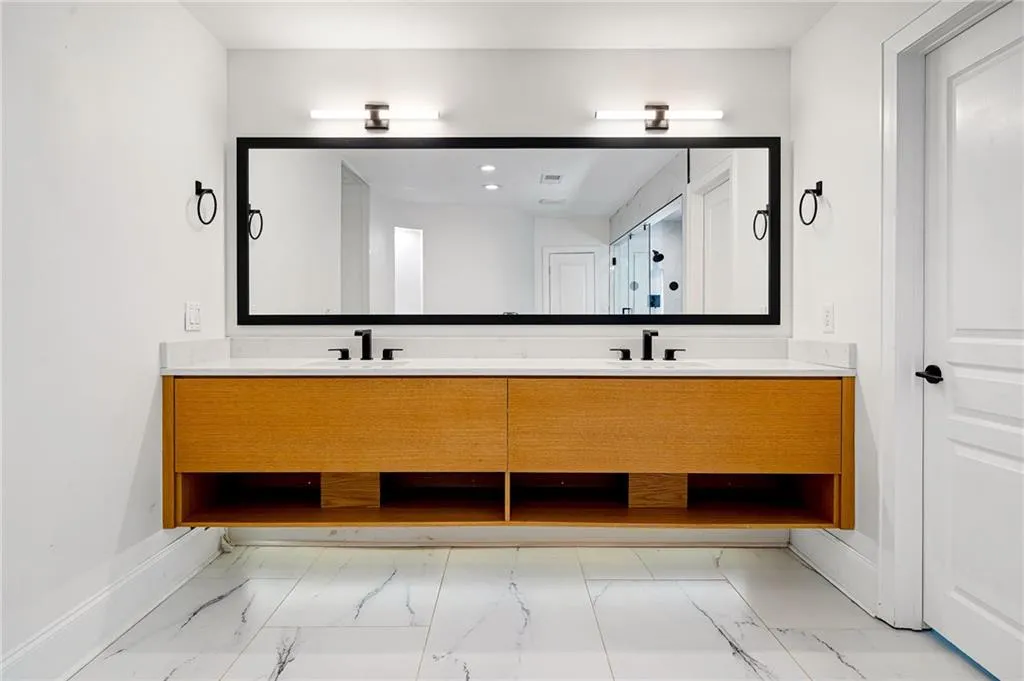 Full bath featuring double vanity and light marble finish floors Full bath featuring double vanity and light marble finish floors