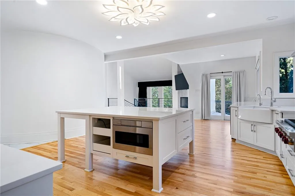 Kitchen with light stone countertops, light wood-style flooring, recessed lighting, white cabinetry, and appliances with stainless steel finishes Kitchen with light stone countertops, light wood-style flooring, recessed lighting, white cabinetry, and appliances with stainless steel finishes