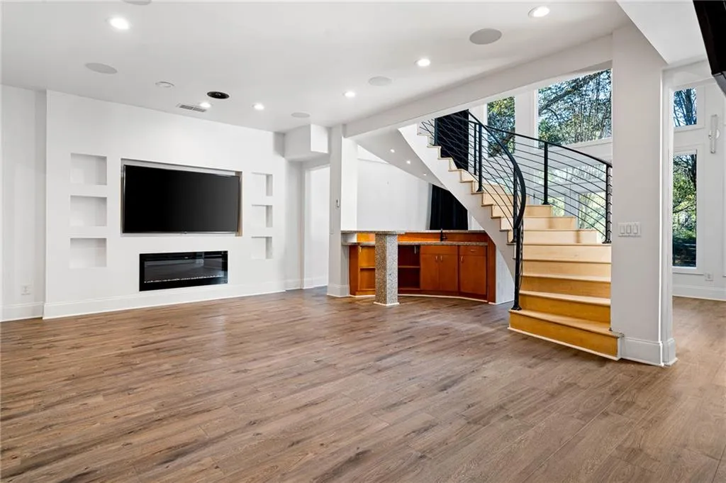 Unfurnished living room featuring recessed lighting, built in features, wood finished floors, stairway, and a glass covered fireplace Unfurnished living room featuring recessed lighting, built in features, wood finished floors, stairway, and a glass covered fireplace