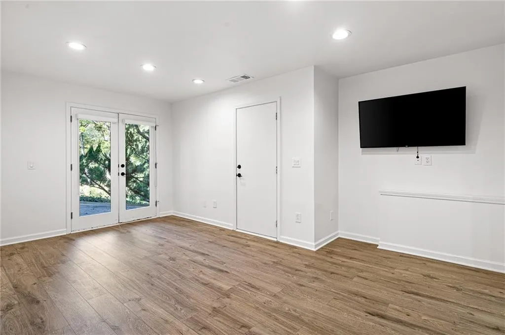 Unfurnished living room with recessed lighting, wood finished floors, and french doors Unfurnished living room with recessed lighting, wood finished floors, and french doors