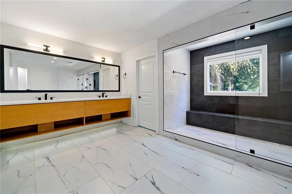 Bathroom with double vanity, walk in shower, and light marble finish flooring Bathroom with double vanity, walk in shower, and light marble finish flooring