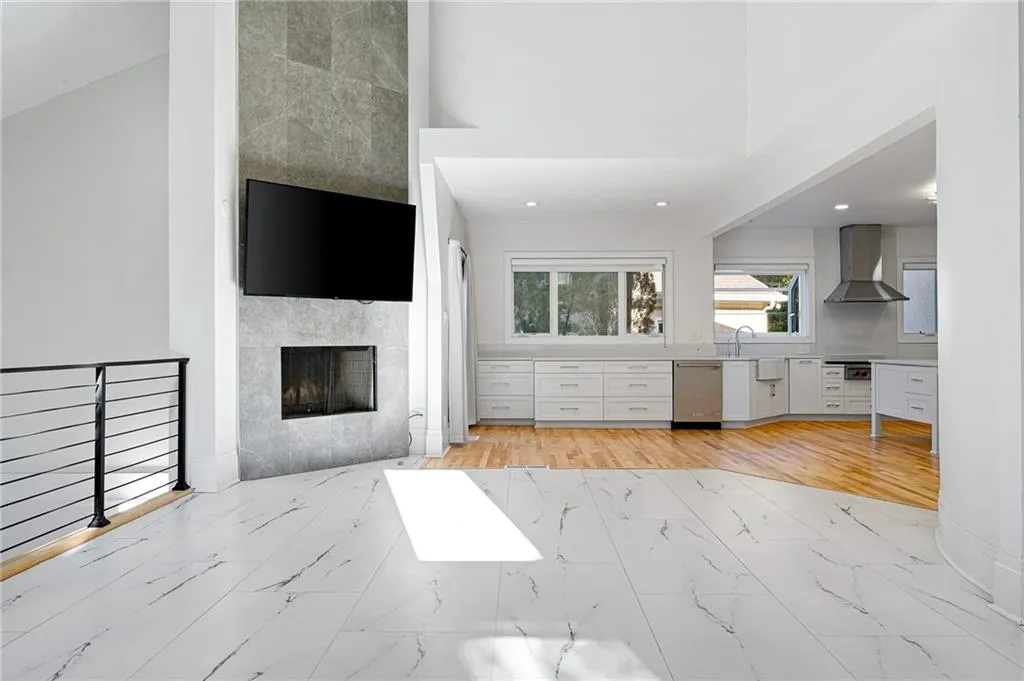 Living room with a fireplace, light marble finish floors, a towering ceiling, and recessed lighting Living room with a fireplace, light marble finish floors, a towering ceiling, and recessed lighting