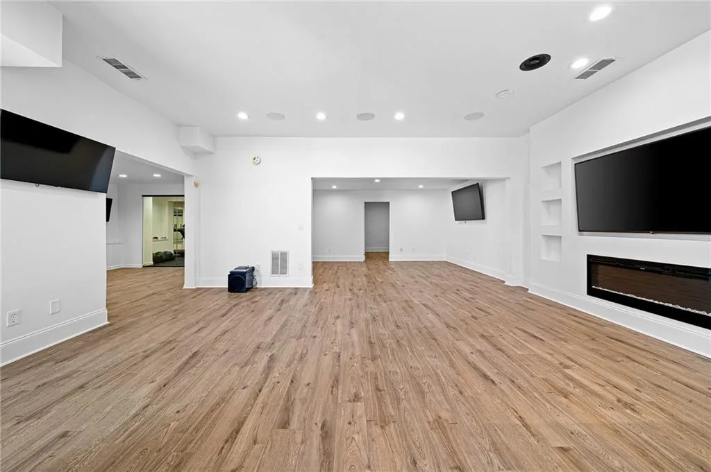 Unfurnished living room featuring recessed lighting, light wood-style flooring, built in features, and a glass covered fireplace Unfurnished living room featuring recessed lighting, light wood-style flooring, built in features, and a glass covered fireplace