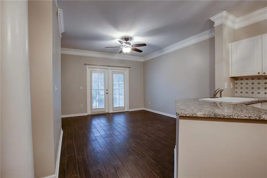 Unfurnished dining area with crown molding, a ceiling fan, and dark wood finished floors