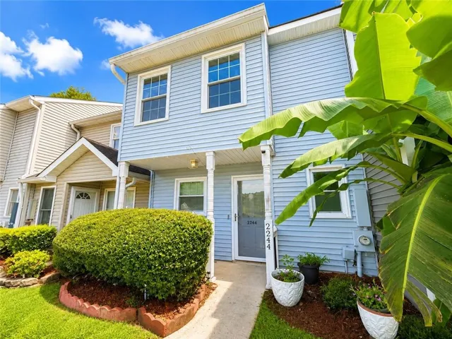 Front exterior with white window trim, covered porch entry, and a concrete walkway