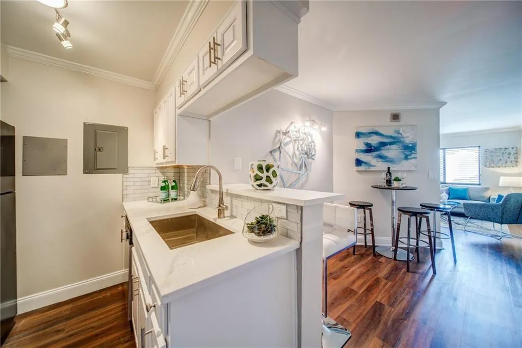 Kitchen featuring dark wood-style floors, a peninsula, crown molding, decorative backsplash, and white cabinets
