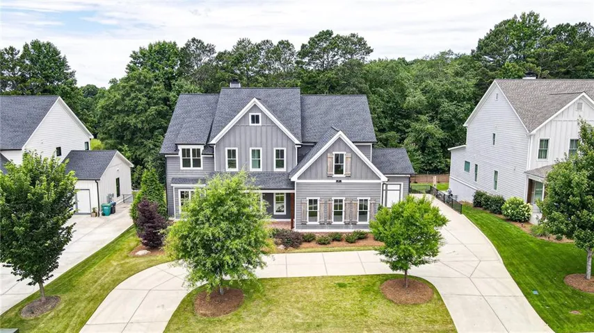Contemporary residence featuring a gray exterior with board and batten accents, a dark shingle roof, and multiple gables