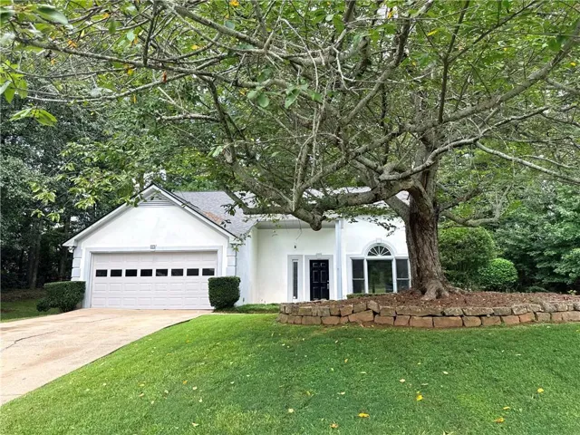 White exterior with an arched window and a prominent mature tree