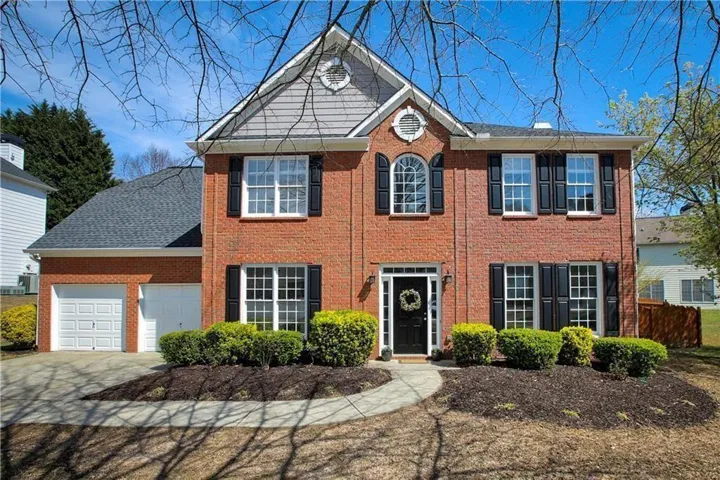 Brick exterior with a shingled roof and a two-car garage