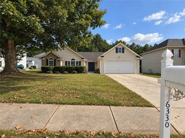 Single-story residence featuring a two-car garage, concrete driveway, and mature landscaping