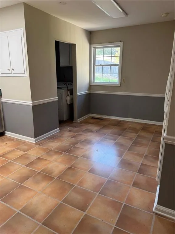 Unfurnished dining area with light tile patterned floors and washer and dryer