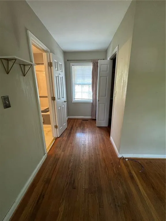 Hallway with dark wood-style flooring and baseboards