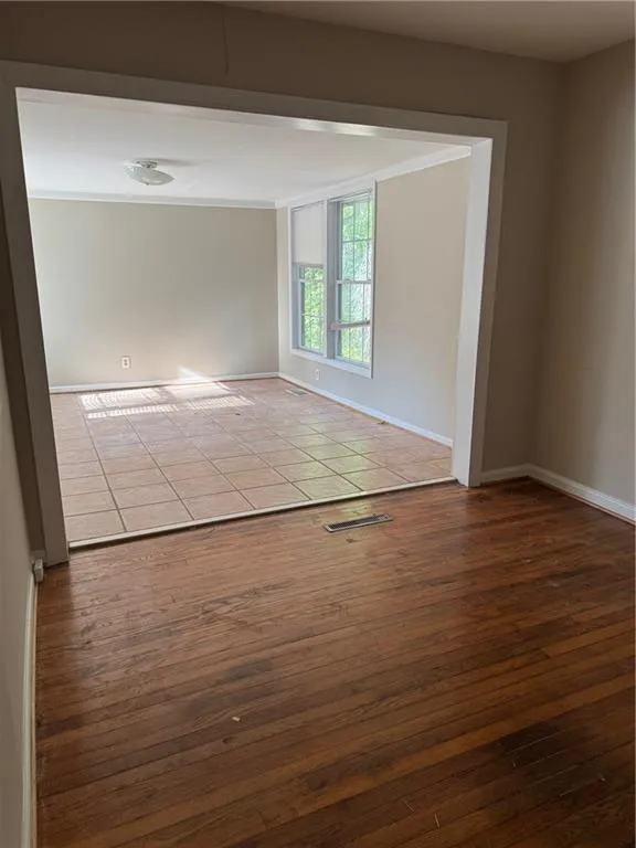 Spare room with dark wood-type flooring and ornamental molding
