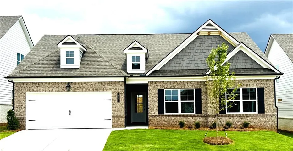 Single-story residence featuring a brick facade with grey shingle and white siding accents