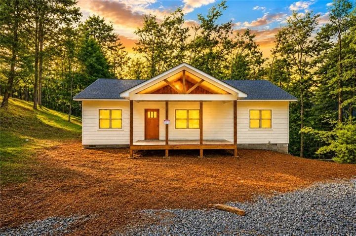 Cottage-style residence featuring a prominent covered porch with exposed wood beams and posts