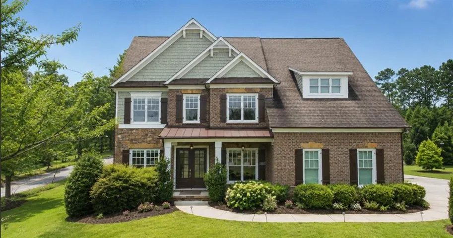 Brick and stone facade featuring gabled dormers and a covered front porch