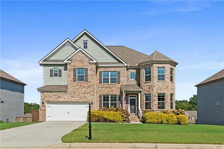 Two-story brick and siding exterior with a prominent turret, front-facing two-car garage, and a concrete driveway