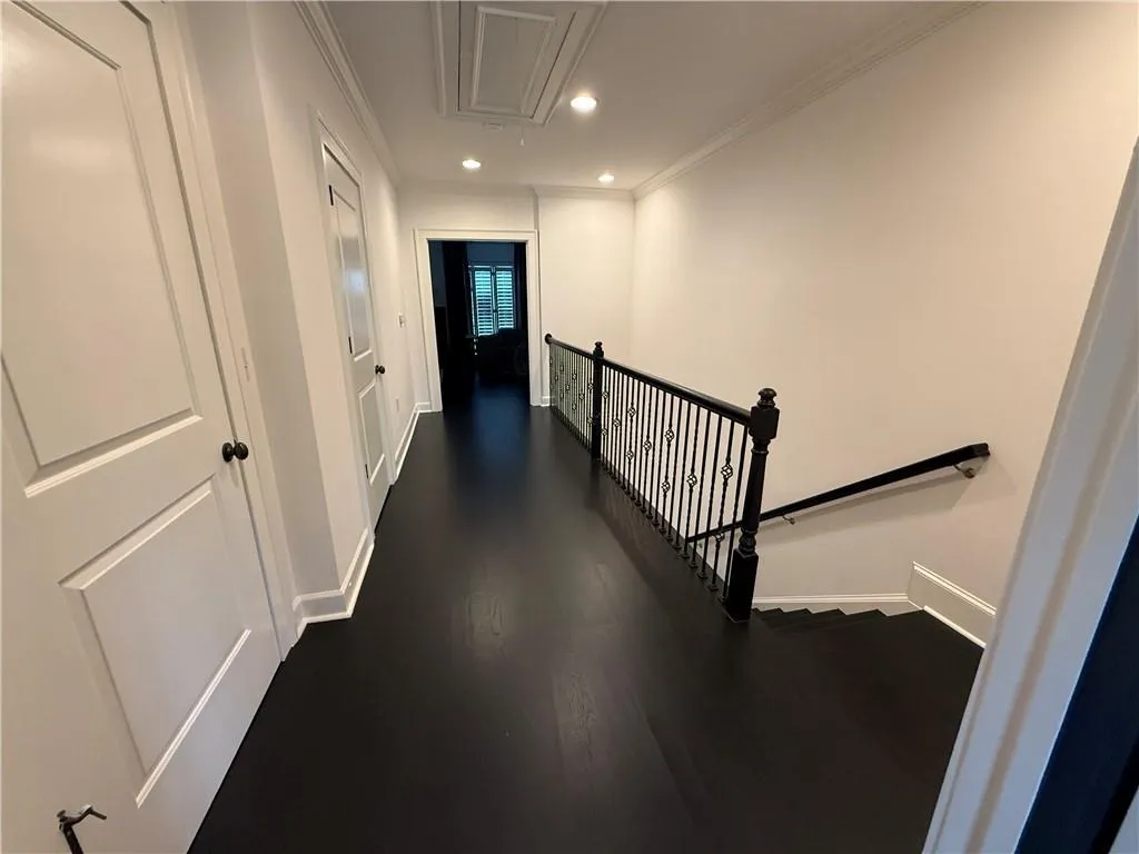 Corridor with attic access, recessed lighting, dark wood-type flooring, ornamental molding, and an upstairs landing