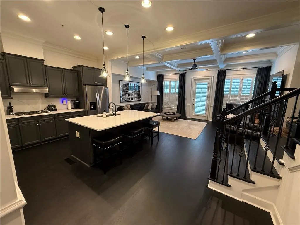 Kitchen featuring dark cabinets, coffered ceiling, beam ceiling, pendant lighting, and a ceiling fan