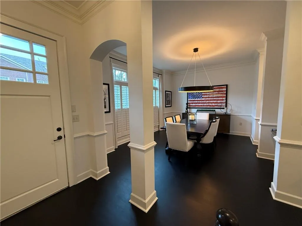 Home office featuring ornamental molding, arched walkways, and dark wood-style flooring