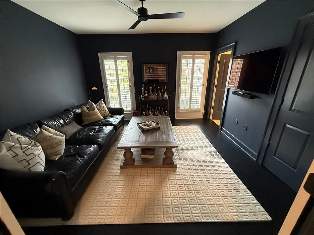 Living area with dark wood finished floors and ceiling fan
