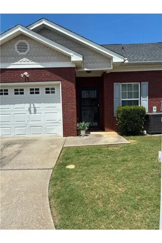 Brick exterior featuring a white paneled garage door, a black security screen door, and light blue window shutters