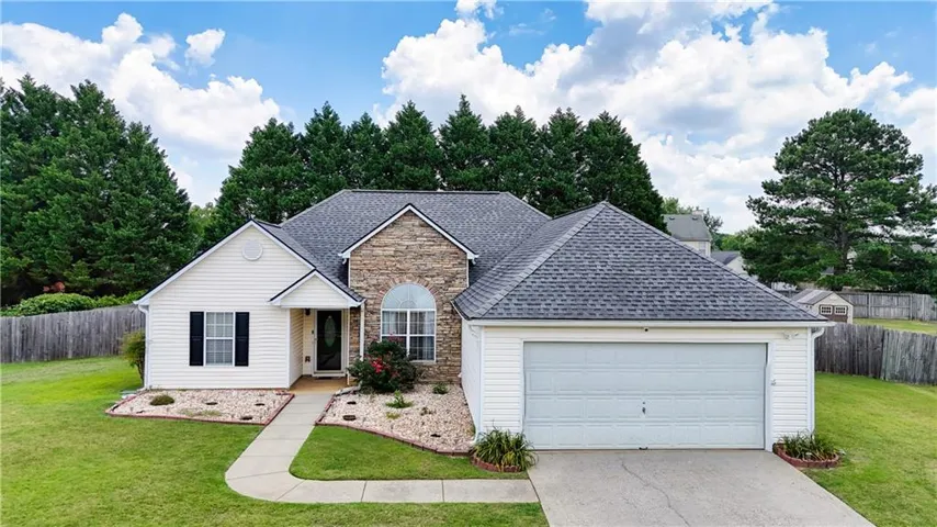 Ranch-style residence featuring a stone and siding facade, a two-car garage, and a charcoal shingle roof