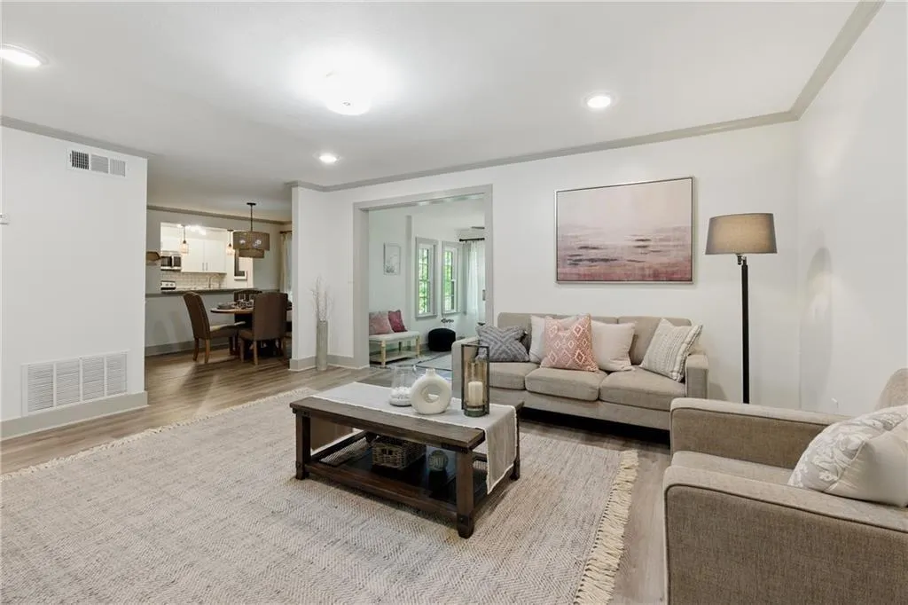 Living room featuring wood finished floors, crown molding, and recessed lighting