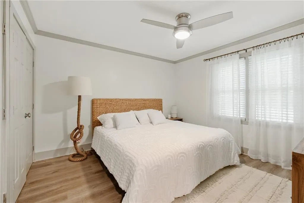 Bedroom with light wood-type flooring, a ceiling fan, crown molding, and a closet