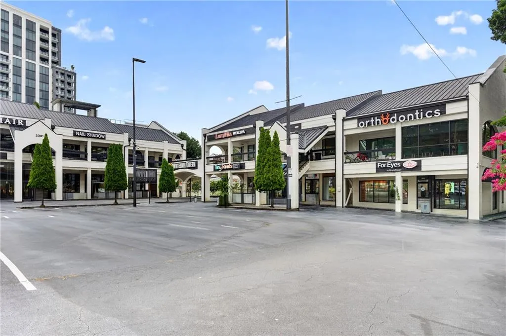 Commercial complex featuring multi-story buildings with black gable roofs and cream-colored facades