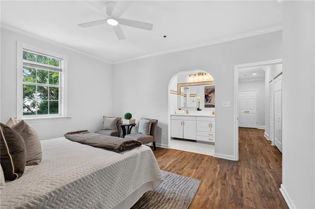 Spacious room featuring wood-finish flooring, a white ceiling fan, and a large window with white trim