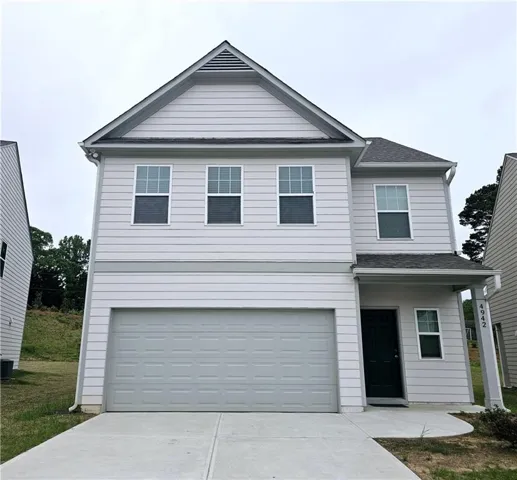 View of front facade with concrete driveway, an attached garage, and roof with shingles