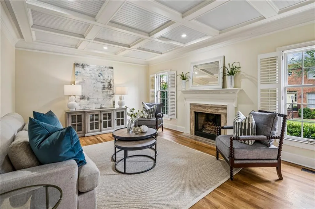 Living room featuring ornamental molding, beamed ceiling, a fireplace, coffered ceiling, and wood finished floors