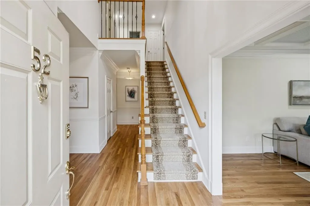Foyer featuring light wood-type flooring, stairway, ornamental molding, and a towering ceiling