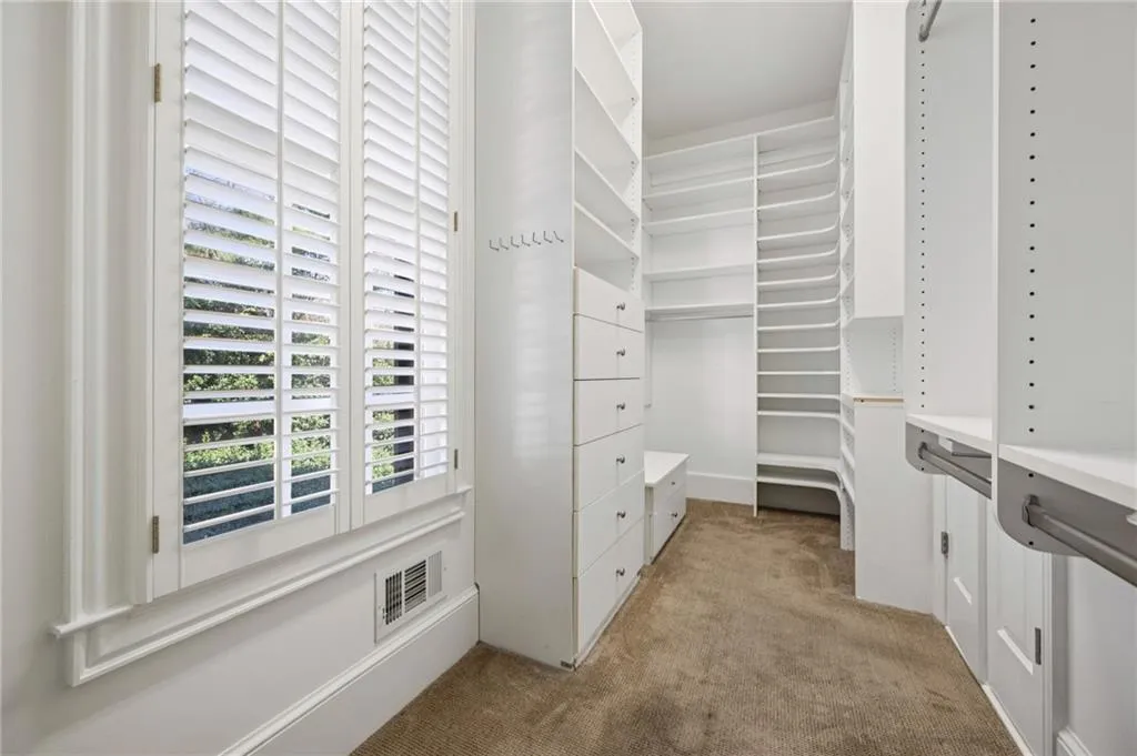 Walk in closet featuring light colored carpet