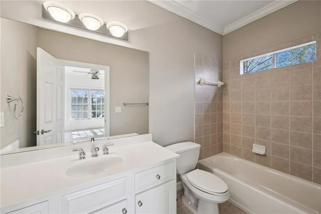 Bathroom featuring plenty of natural light, vanity, crown molding, and tub / shower combination