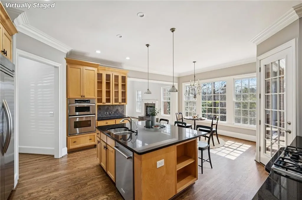 Kitchen with open shelves, glass insert cabinets, ornamental molding, dark wood finished floors, and an island with sink