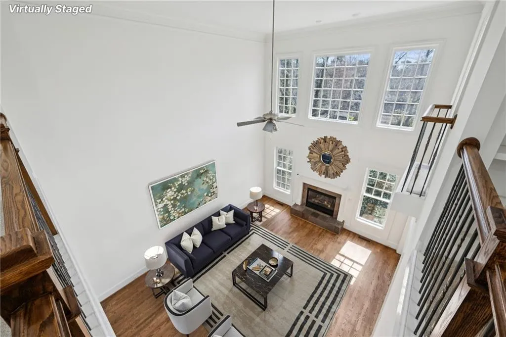 Living room featuring wood finished floors, a glass covered fireplace, a high ceiling, plenty of natural light, and ornamental molding