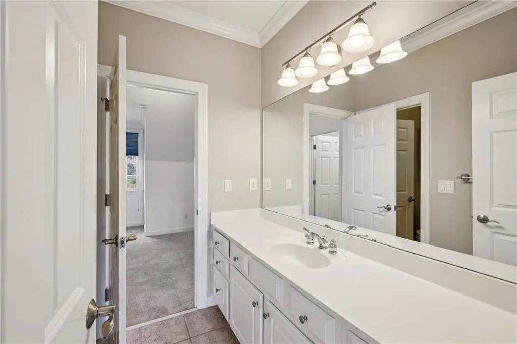 Bathroom with vanity, crown molding, and light colored carpet