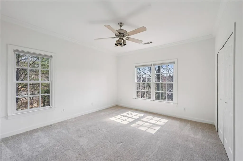 Unfurnished bedroom featuring crown molding, a closet, light carpet, and a ceiling fan