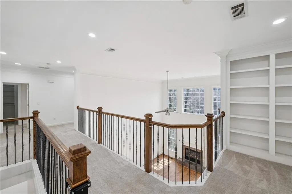 Hall with recessed lighting, ornamental molding, light colored carpet, and an upstairs landing
