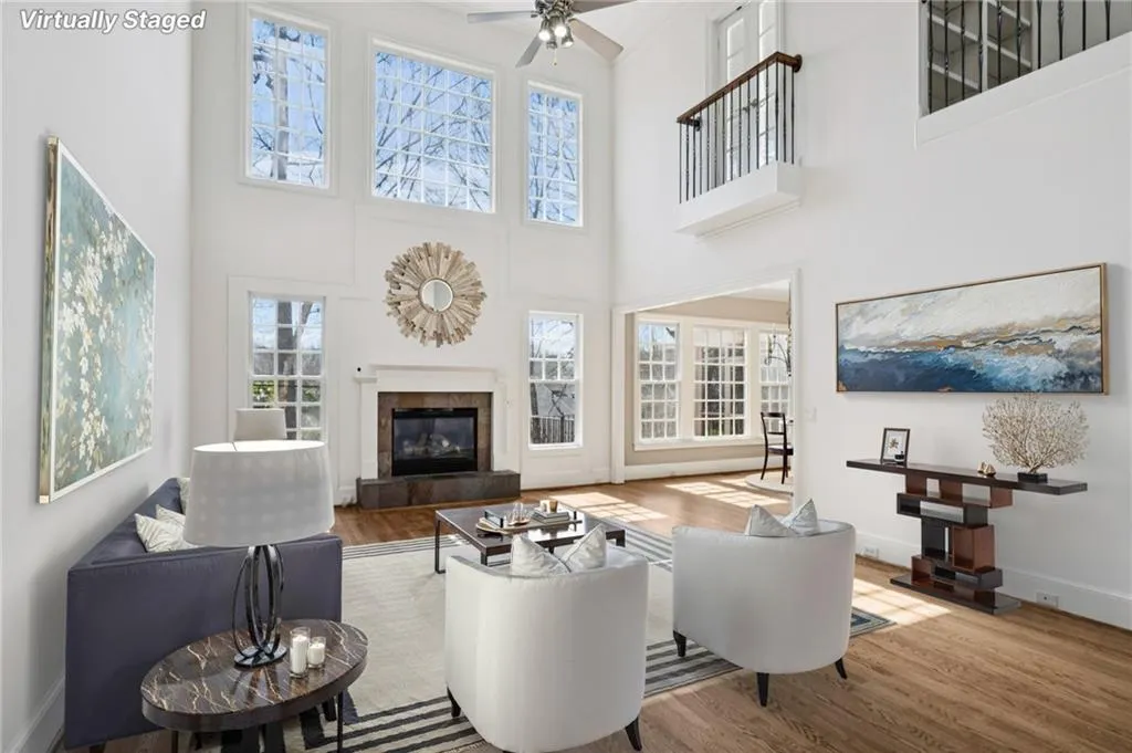 Living area with a fireplace, wood finished floors, a ceiling fan, and a high ceiling
