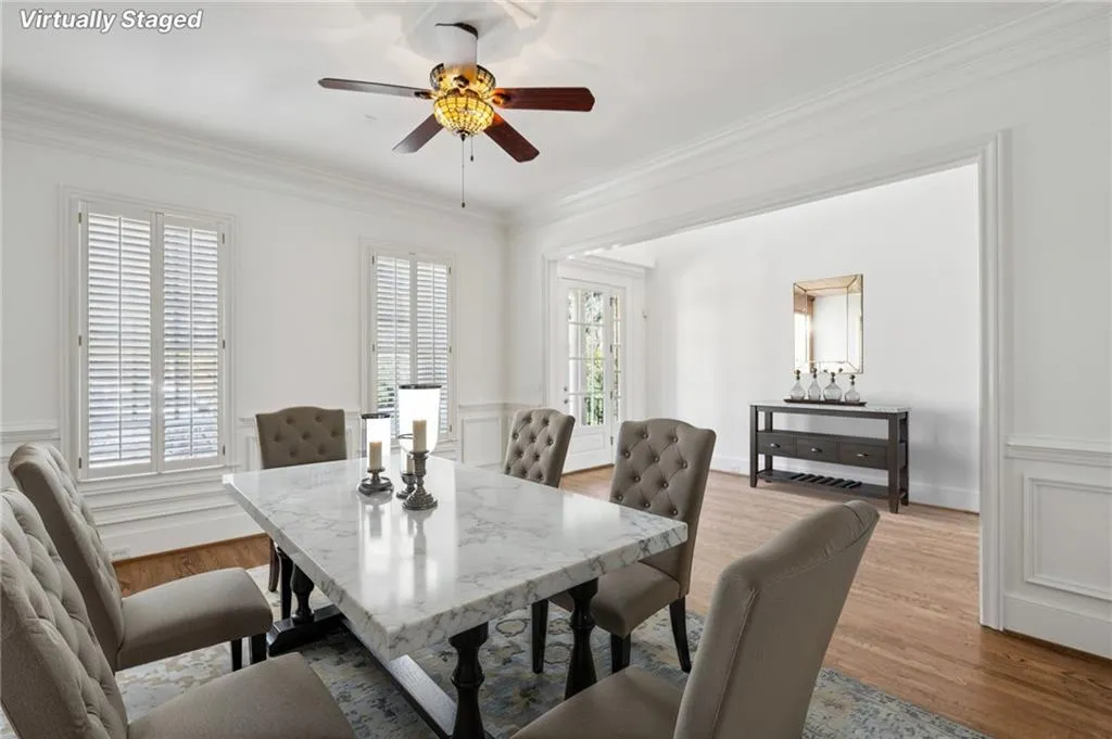 Dining area with wood finished floors, crown molding, ceiling fan, and a wainscoted wall