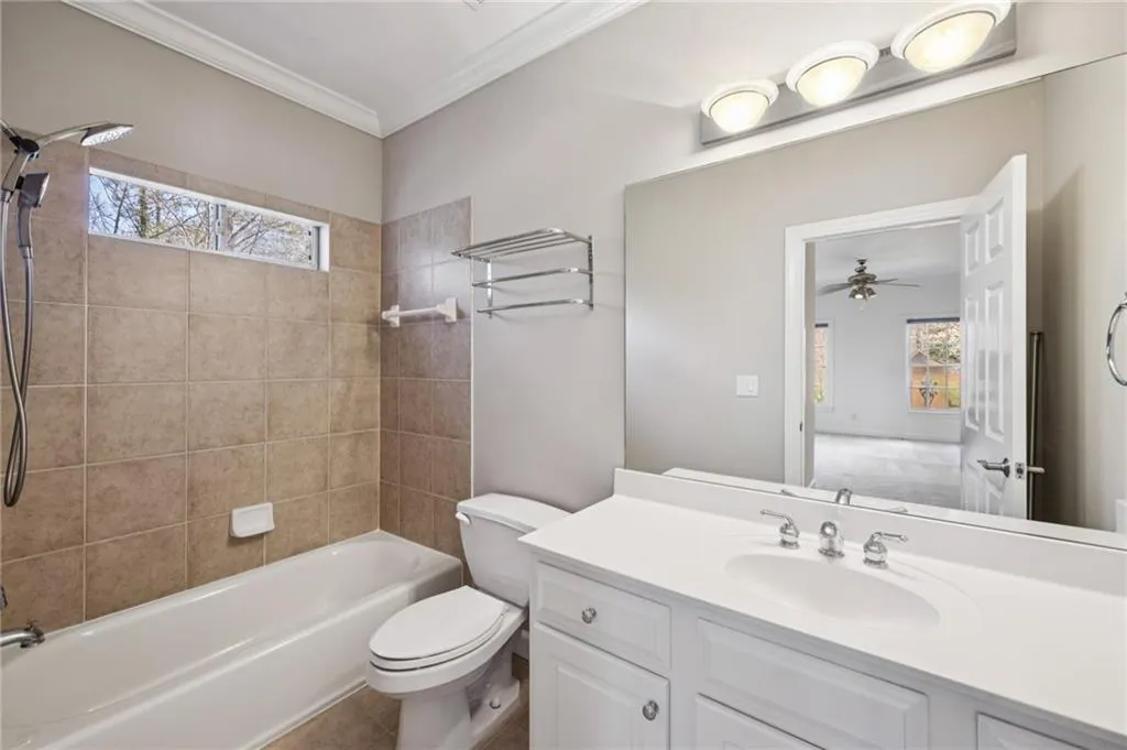Full bath with plenty of natural light, vanity, washtub / shower combination, and ornamental molding