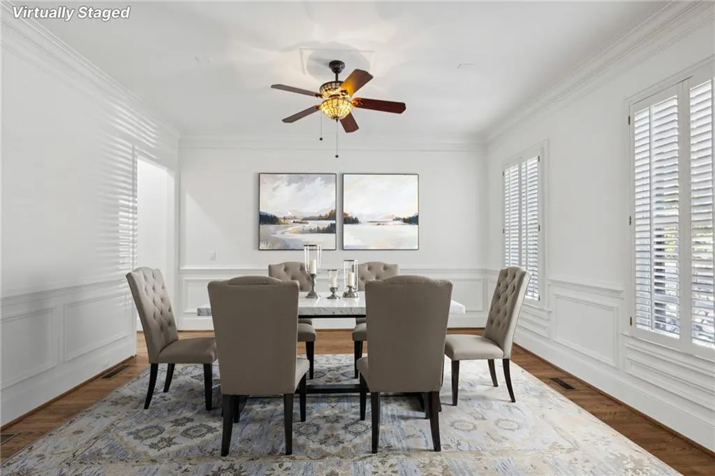 Dining area featuring a decorative wall, a wainscoted wall, a ceiling fan, wood finished floors, and crown molding
