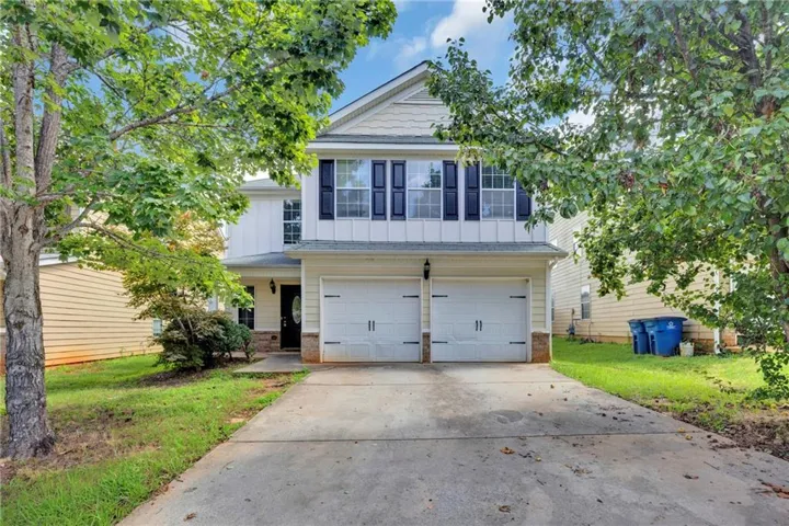 Two-story residence featuring a two-car garage with overhead doors, a concrete driveway, and a covered entry
