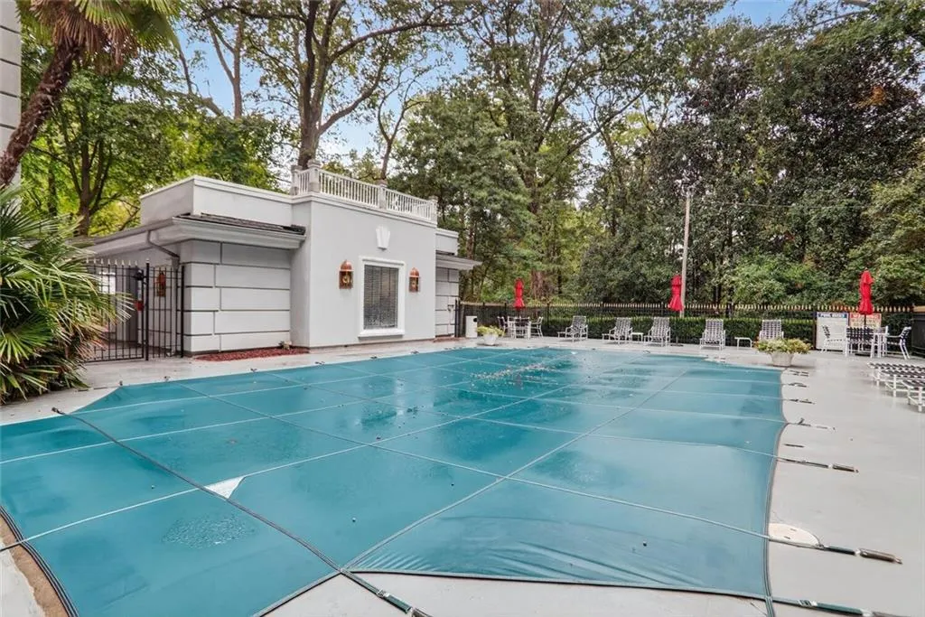 Community pool with a patio area and view of wooded area